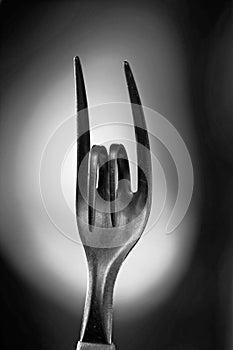 Vertical greyscale shot of a bent metal fork symbolizing the sign of rock music