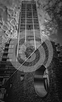 Vertical greyscale shot of a high rise building under the gloomy cloudy sky