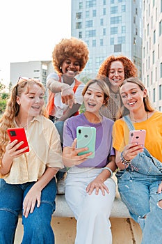 Vertical. Group of teenage girls using a mobilephone. Young women watching their smart phones. Female friends sharing on