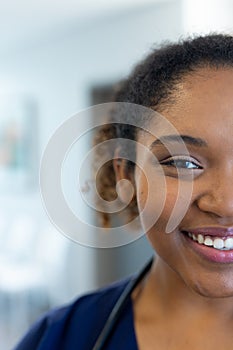 Vertical half face portrait of smiling african american female doctor in corridor, with copy space