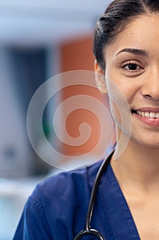 Vertical half face portrait of smiling biracial female doctor in hospital ward, copy space photo