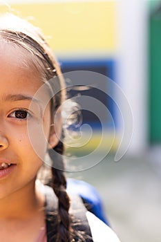 Vertical half face portrait of smiling cauasian elementary schoolgirl in schoolyard, copy space photo