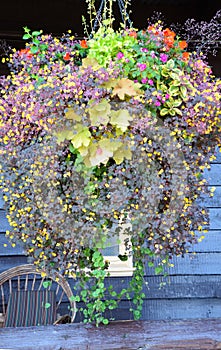 Vertical-Hanging basket full of flowers hang before an old wooden hotel.