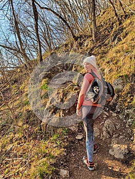 VERTICAL: Happy woman stops while hiking up a forest trail with her puppy.