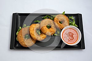 Vertical Hero shot of an appetizer platter of onion rings with lettuce and tomato chutney on a minimal white background with
