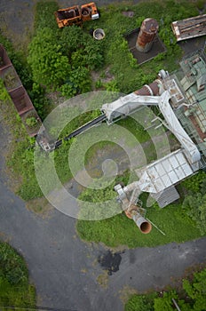 Vertical high angle shot of an abandoned factory with bright green plants growing