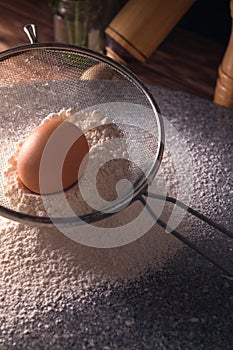 Vertical high angle shot of an egg on flour on a wooden table