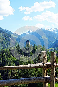 Vertical high angle shot of the green forest in the mountains behind the wooden fence