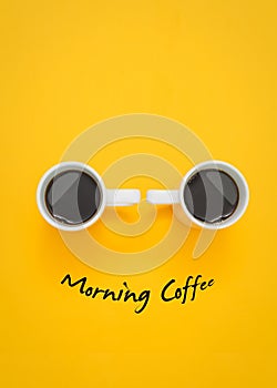 Vertical high angle shot of two cups of coffee on a yellow background with \