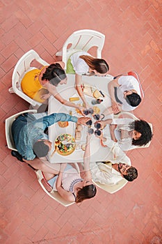 Vertical high angle view of a group of friends having a dinner party celebration at home terrace, toasting or clinking