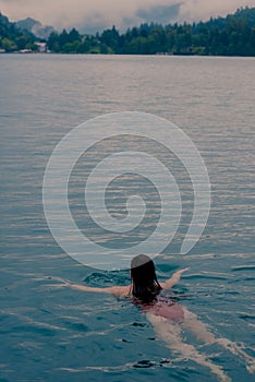 Vertical high-angle view of a woman from behind swimming in the Lake Bled