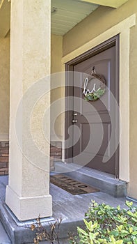 Vertical Home entrance with doorstep small porch and brown wooden front door with wreath