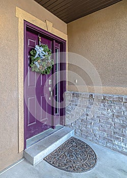 Vertical Home facade with purple front door decorated with wreath and beside a sidelight
