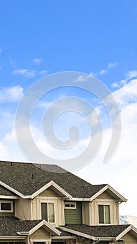 Vertical House exterior with view of the dark pitched roof against a cloudy blue sky