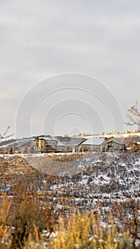 Vertical Houses on top of hill surrounded by snowy terrain with cloudy sky background