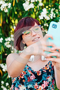 Vertical image of a beautiful young woman with glasses taking a selfie photo with her phone