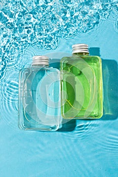 Vertical image of beauty product bottles in water with copy space background on blue background