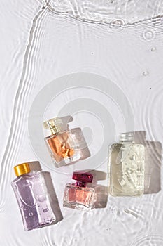 Vertical image of beauty product bottles in water with copy space background on white background