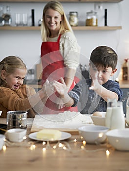 Vertical image of children clasping using flour while baking cookies