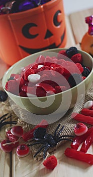 Vertical image of close of candy and halloween pumpkin basket with sweets on rustic background