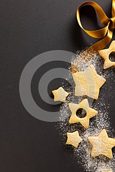 Vertical image of close up of christmas cookies with copy space and ribbon on black background
