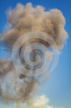 Vertical image of Column of smoke with tornado against blue sky from munitions explosion photo