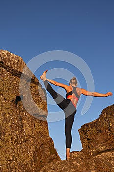 vertical image with copyspace of woman doing yoga in sportswear between some rocks of a cliff