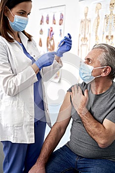 Vertical image of doctor preparing syringe for senior patient