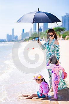 Vertical image. Family travel at the sea and beach. Aunt and granddaughters playing by seaside.