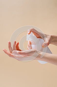 Vertical image of female hands applying lotion to skin on beige isolated background. Natural skincare products concept. Image for