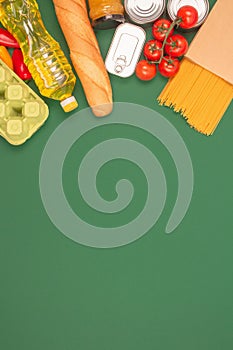 Vertical image with groceries, food donations on green background with copy space - pasta, vegatables, canned food