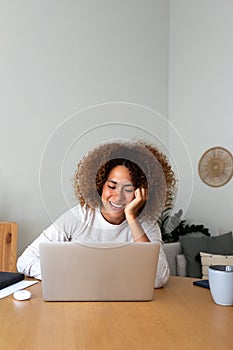 Vertical image of happy african american woman working at home office. Multiracial female entrepreneur using laptop