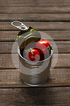 Vertical image.Metal can full of fresh ripe tomatoes on the wooden table