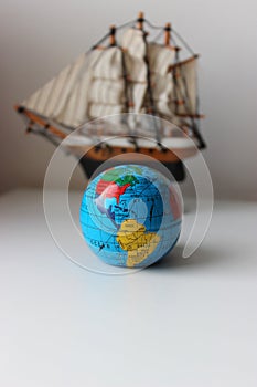 Vertical Image Of Miniature Globe In Front Of Mast Ship Model Isolated On White Backdrop