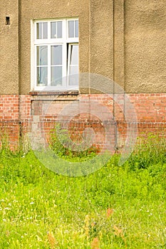 Vertical image of an old building with grungy brick wall and broken window