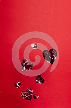 Vertical image.Paper shiny hearts against red background.Empty space