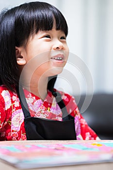 Vertical image. Portrait of Asian student girl sweet smile. Little artist wearing black apron. Kid doing watercolor art