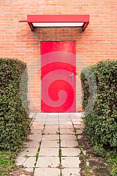 Vertical image. Red door surrounded by orange brick wall. photo