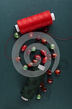 Vertical image.Red and green thread, buttons on the dark surface.Handmade concept