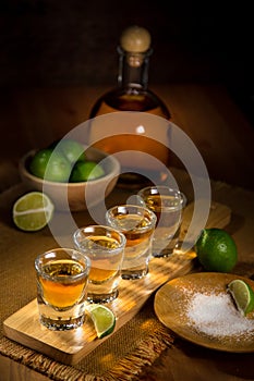 Vertical image of a serving of gold Tequila shots spread out and ready to drink at a party