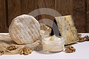 Vertical image of set of delicious fresh cheese,walnut on the white table against wooden background.Empty space