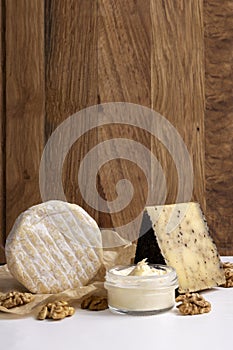 Vertical image of set of delicious fresh cheese,walnut on the white table against wooden background.Empty space