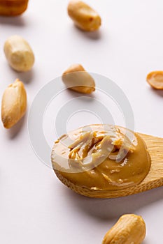 Vertical image of spoon with peanut butter and nuts on white surface