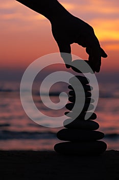 Vertical image of stacking rocks on the beach with a sunset ocean