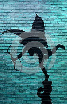 Vertical image of turquoise blue brick wall with the painting of cupid`s silhouette photo