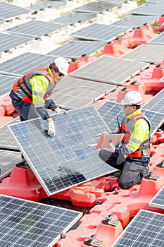 Vertical image of two technician workers help to check and maintenance solar cell panels that set up over area of water reservoir