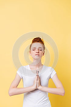 Vertical image of upset ginger woman in t-shirt praying photo