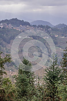 Vertical image of the village above the rice terraces in Laohuzui area, China photo