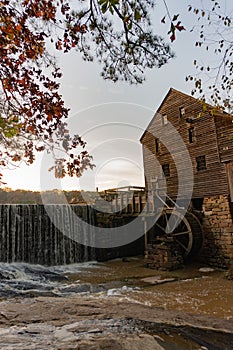 Vertical image of a waterfall at the historic Yates Mill County Park in Wake County, North Carolina at sunset in autumn