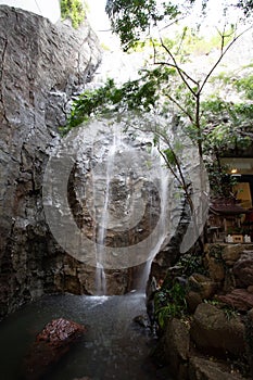 Vertical image of a waterfalls  with tree with a high rock wall